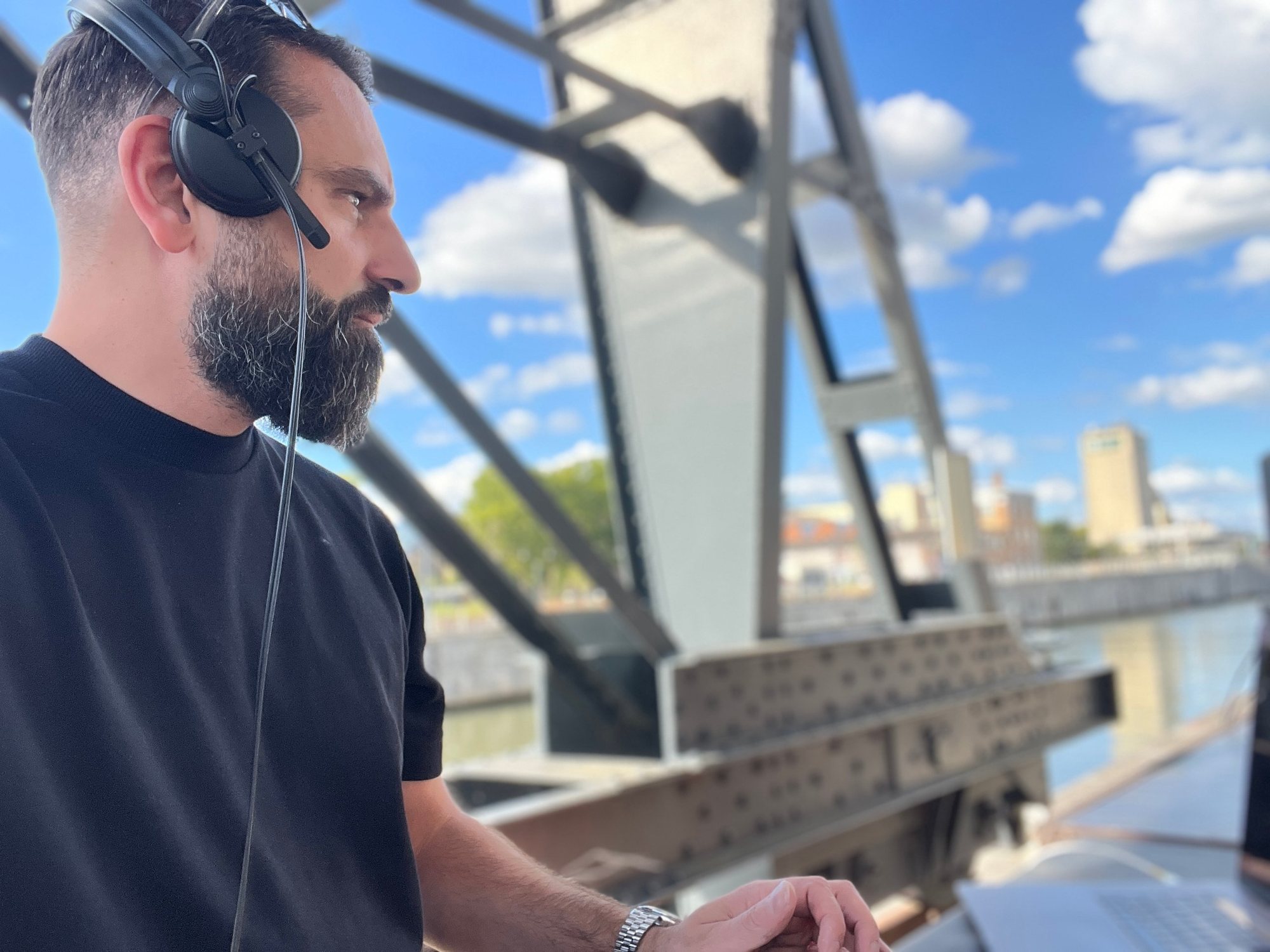 Alter Melego in profile with headphones at an open-air set